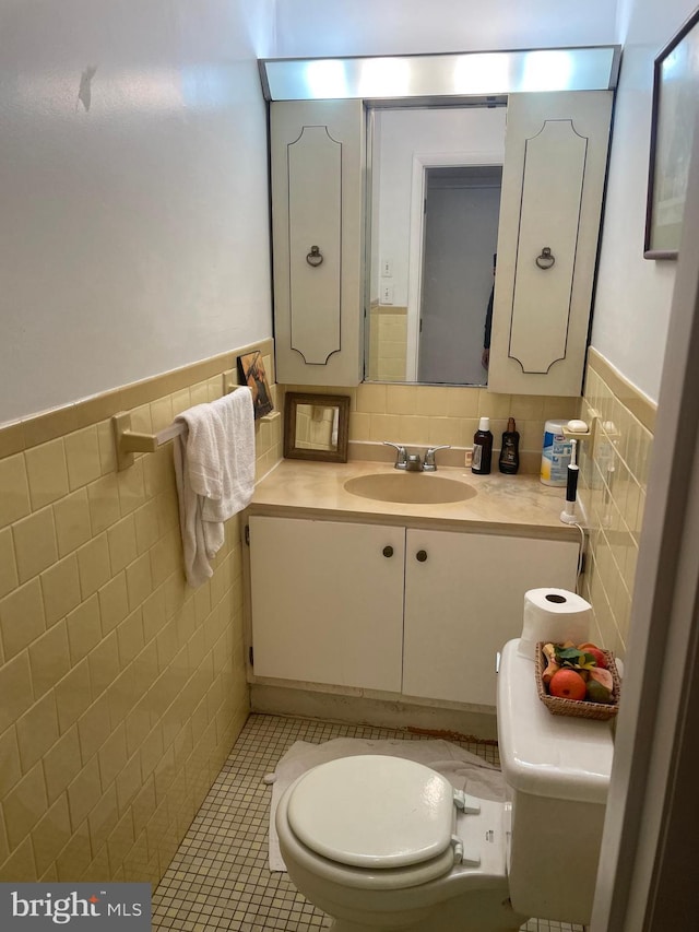 bathroom featuring tile patterned flooring, vanity, toilet, and tile walls