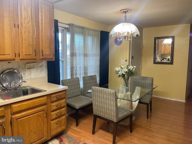 dining space with light hardwood / wood-style flooring, a notable chandelier, and sink