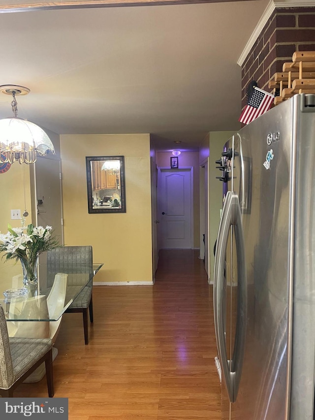 kitchen with hardwood / wood-style flooring, stainless steel fridge, and an inviting chandelier