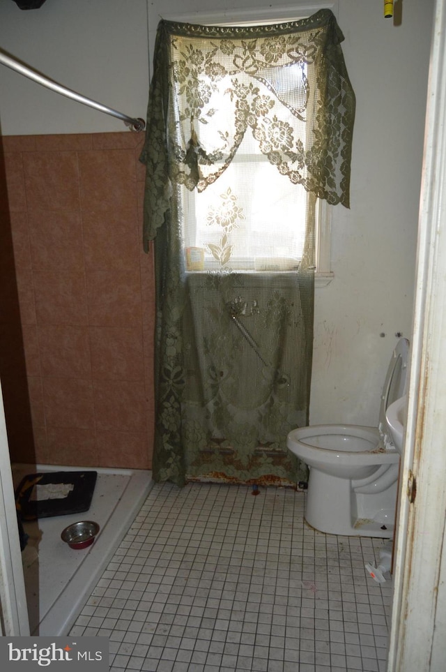 bathroom featuring tile patterned floors, toilet, and tiled shower