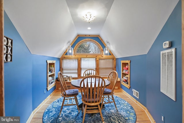 dining area featuring light hardwood / wood-style floors, lofted ceiling, and a chandelier