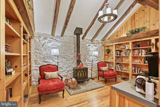 living area featuring a wood stove, vaulted ceiling with beams, and hardwood / wood-style flooring