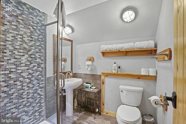 bathroom with sink, walk in shower, vaulted ceiling, toilet, and tile walls