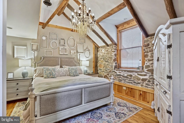 bedroom featuring light wood-type flooring, vaulted ceiling with beams, an inviting chandelier, and wood walls