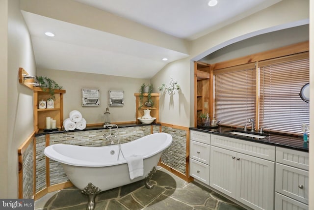 bathroom featuring a washtub, vanity, and vaulted ceiling