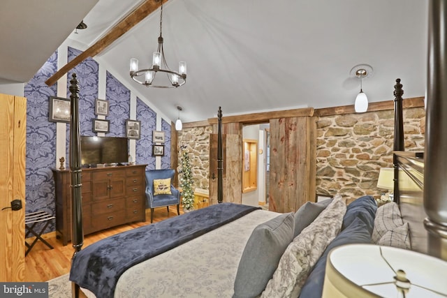 bedroom featuring a barn door, hardwood / wood-style floors, lofted ceiling with beams, and a notable chandelier