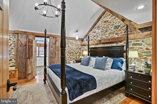 bedroom with light hardwood / wood-style floors, vaulted ceiling, and a notable chandelier