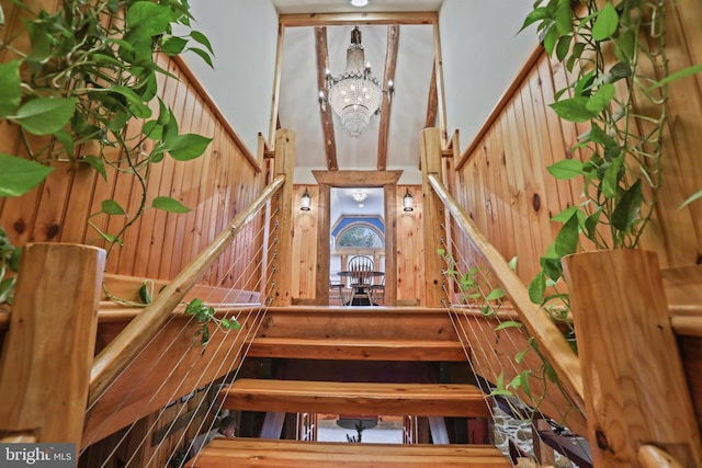 staircase featuring a notable chandelier and wood walls