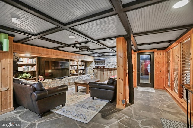 living room with beamed ceiling, built in features, coffered ceiling, and wood walls