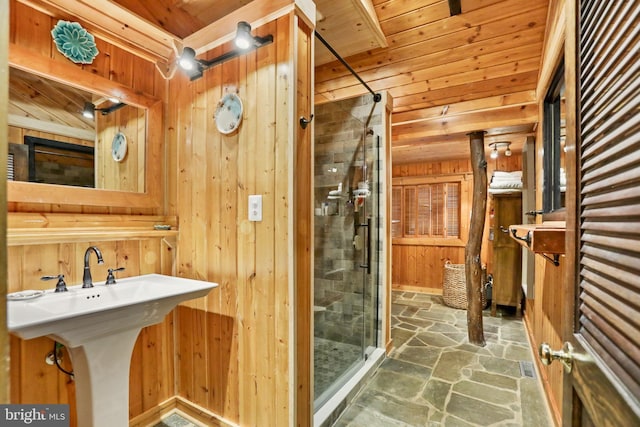 bathroom featuring a tile shower, wood walls, and sink