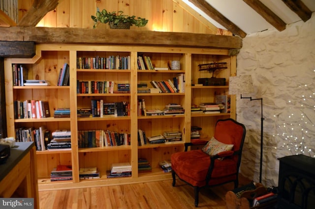 living area featuring a wood stove, hardwood / wood-style floors, and vaulted ceiling with beams