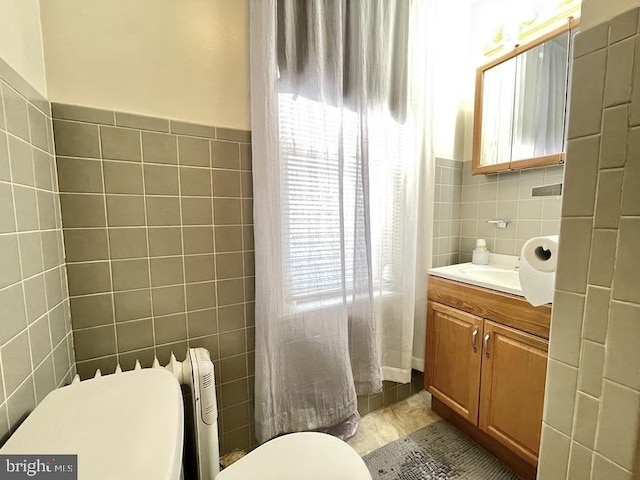 bathroom with tile walls, vanity, toilet, and a healthy amount of sunlight