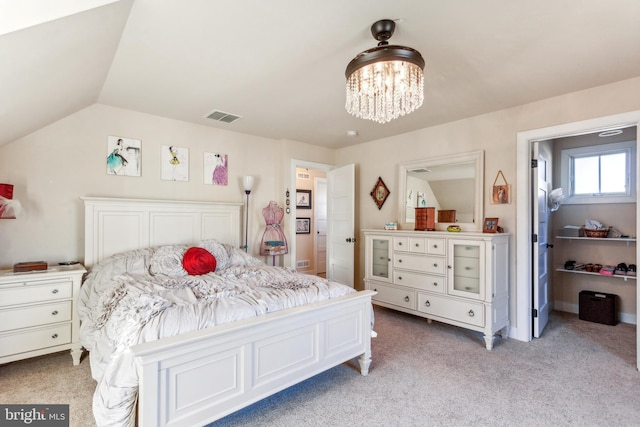 carpeted bedroom with an inviting chandelier and vaulted ceiling