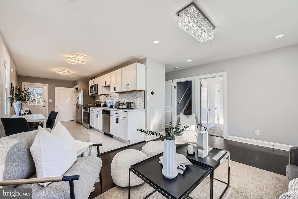 living room featuring sink, a notable chandelier, and light wood-type flooring