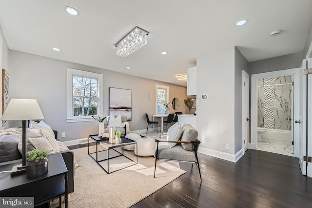 living room with a wealth of natural light, dark hardwood / wood-style floors, and an inviting chandelier