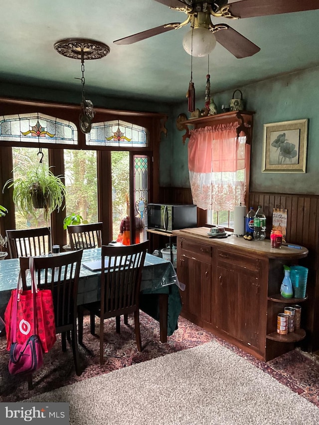 carpeted dining room featuring wood walls