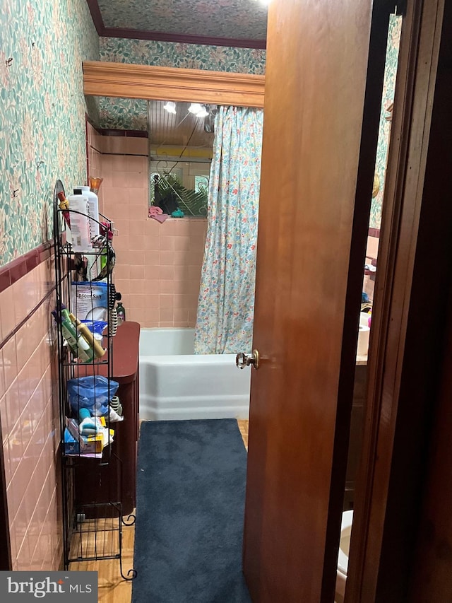 bathroom featuring shower / bath combination with curtain and tile walls