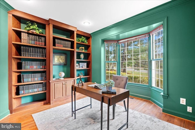 home office with light hardwood / wood-style flooring and built in features