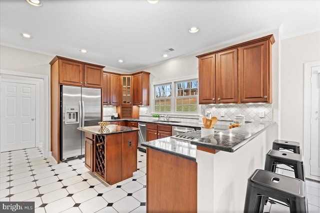 kitchen with a kitchen island, kitchen peninsula, stainless steel appliances, and dark stone counters