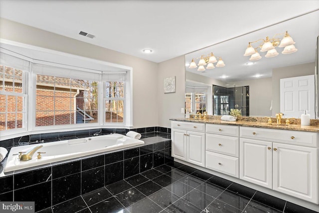 bathroom featuring tiled tub and vanity