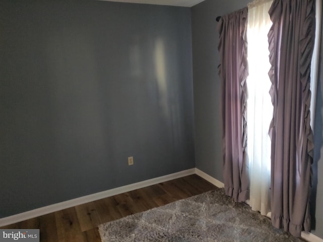 unfurnished room featuring baseboards, plenty of natural light, and wood finished floors