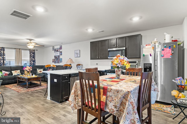 kitchen featuring appliances with stainless steel finishes, a center island, light hardwood / wood-style flooring, and ceiling fan