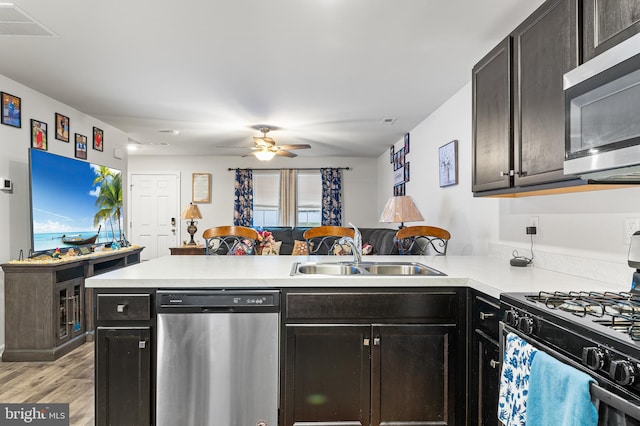 kitchen featuring kitchen peninsula, stainless steel appliances, ceiling fan, sink, and light hardwood / wood-style floors