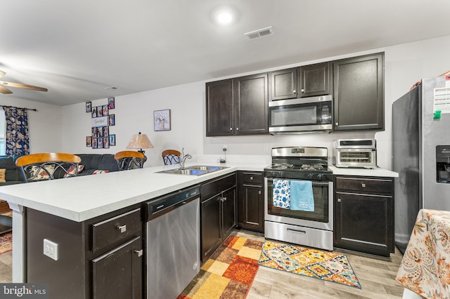 kitchen featuring kitchen peninsula, appliances with stainless steel finishes, light hardwood / wood-style flooring, and sink