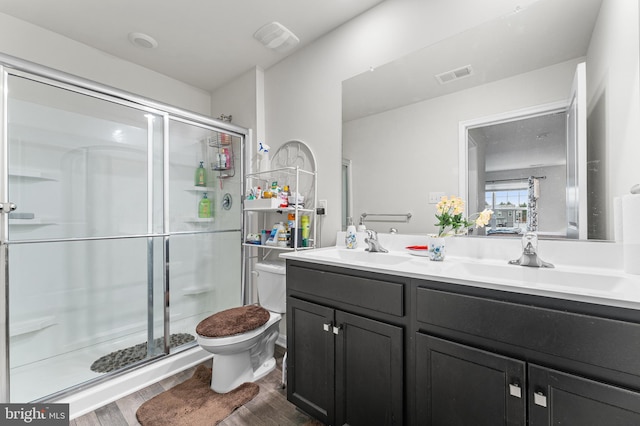 bathroom featuring hardwood / wood-style floors, vanity, a shower with door, and toilet