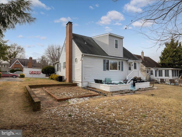 back of property featuring central air condition unit and a yard