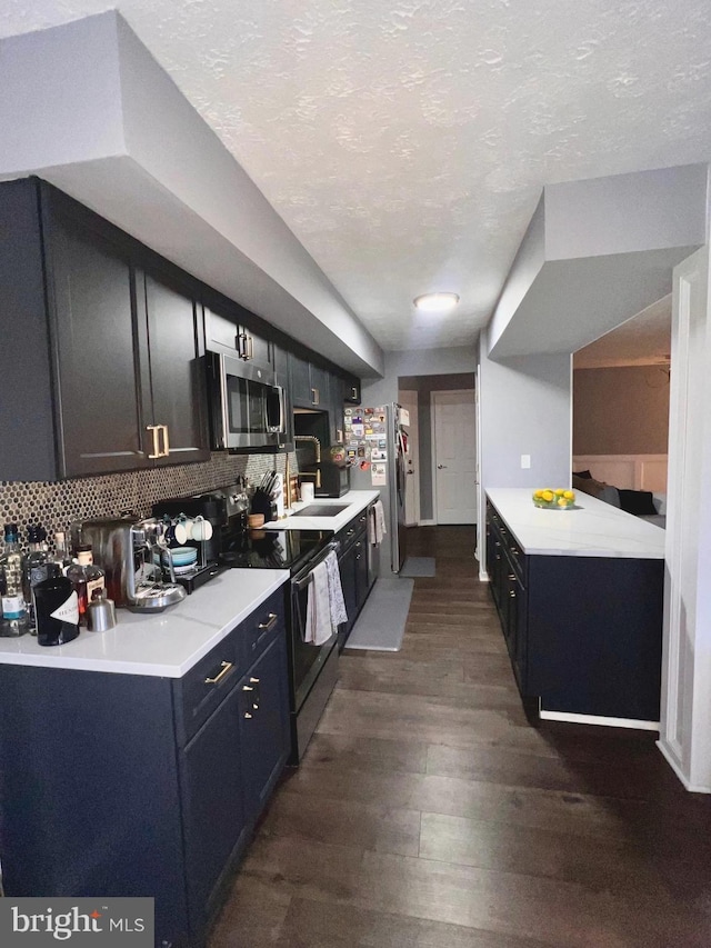 kitchen with a textured ceiling, dark wood-type flooring, appliances with stainless steel finishes, and tasteful backsplash