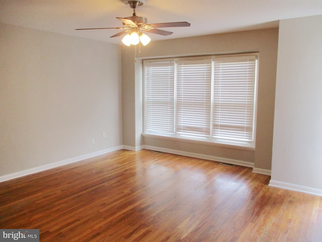 spare room featuring hardwood / wood-style floors, ceiling fan, and a healthy amount of sunlight