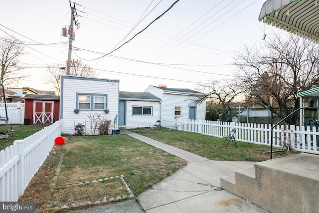 view of front facade featuring a front yard and a storage shed