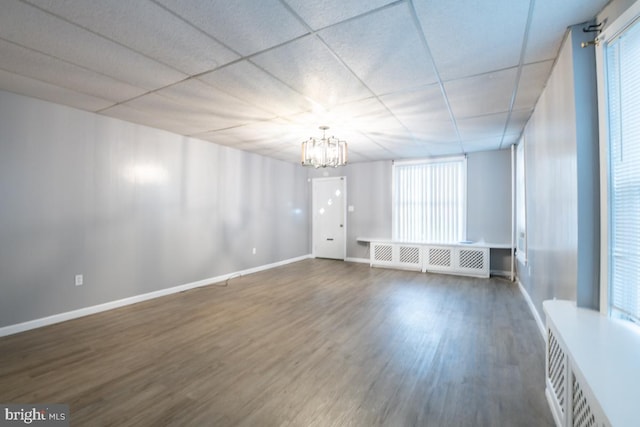 unfurnished room featuring radiator, a paneled ceiling, dark hardwood / wood-style floors, and a notable chandelier