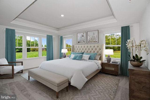 bedroom with a raised ceiling, light colored carpet, and multiple windows