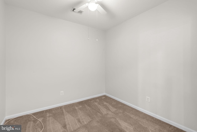 carpeted spare room with visible vents, baseboards, and ceiling fan