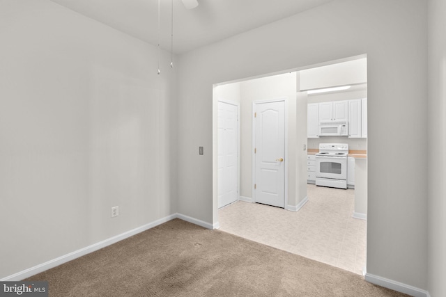 spare room featuring light carpet, baseboards, and ceiling fan