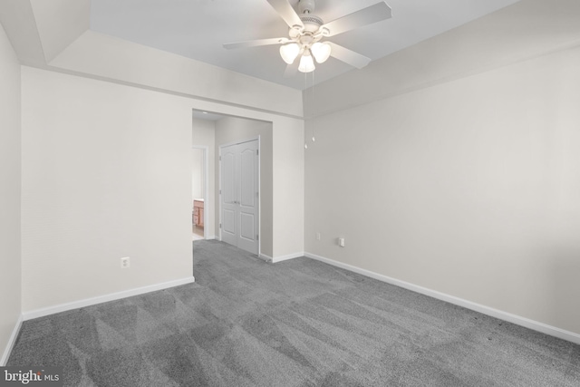 carpeted spare room featuring ceiling fan and baseboards
