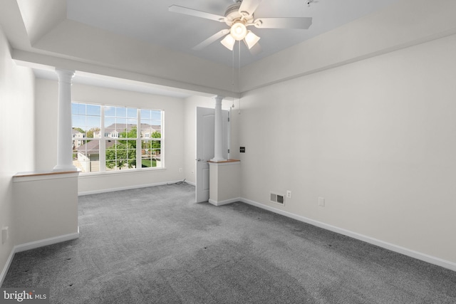 carpeted spare room with baseboards, visible vents, a ceiling fan, and ornate columns