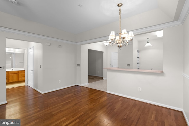 unfurnished dining area featuring baseboards, a notable chandelier, and wood finished floors
