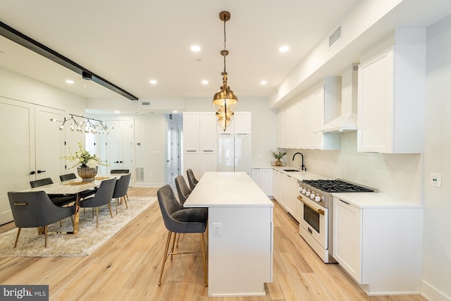 kitchen with high end range, light wood-type flooring, custom exhaust hood, a center island, and hanging light fixtures