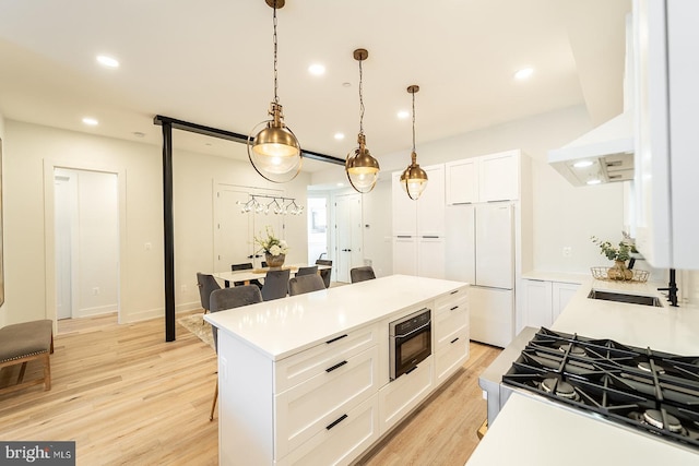 kitchen featuring black appliances, light hardwood / wood-style floors, decorative light fixtures, a kitchen island, and white cabinetry