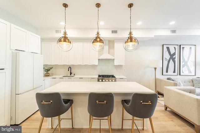 kitchen with white cabinets, light wood-type flooring, white fridge, and custom exhaust hood