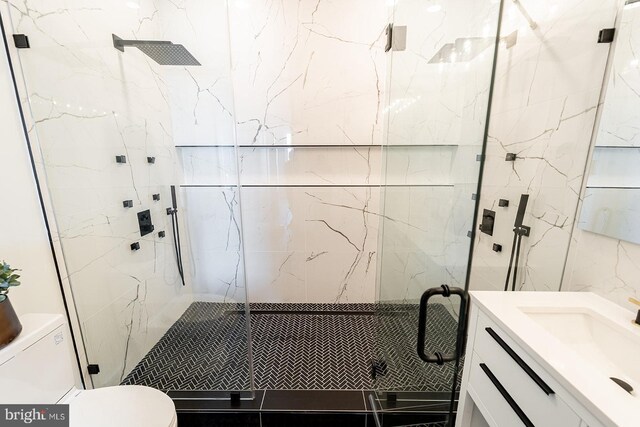 bathroom featuring vanity, toilet, a shower with door, and tile walls