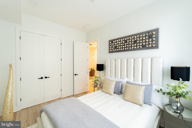 bedroom with light hardwood / wood-style floors and a closet