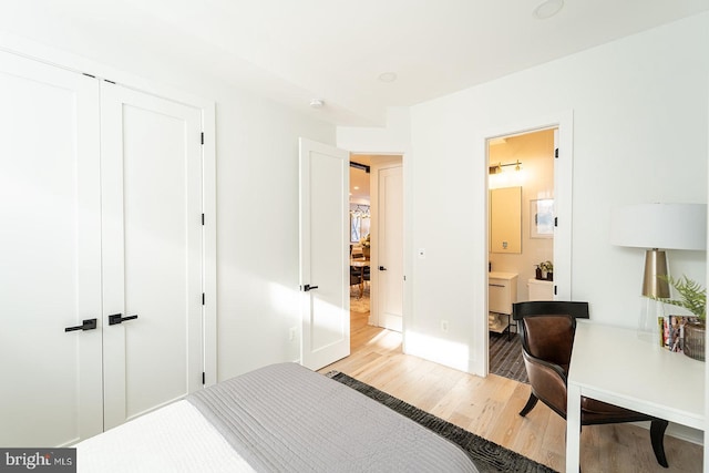 bedroom with connected bathroom, light hardwood / wood-style floors, and a closet