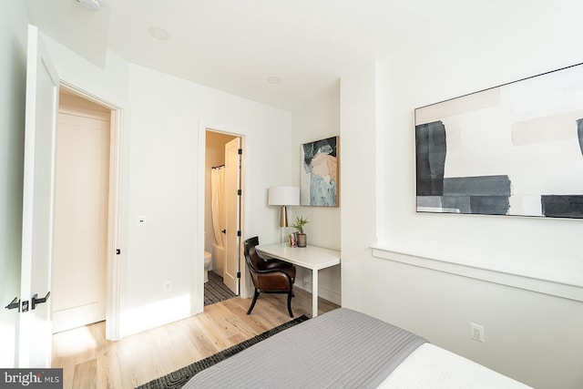 bedroom with connected bathroom and light wood-type flooring