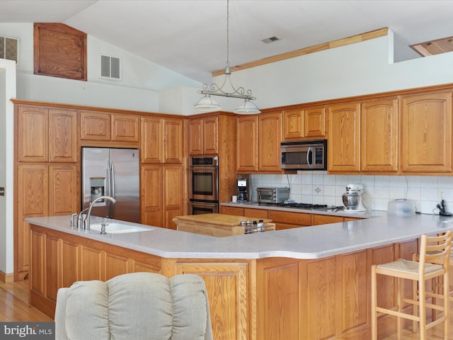 kitchen featuring sink, decorative backsplash, light wood-type flooring, decorative light fixtures, and stainless steel appliances