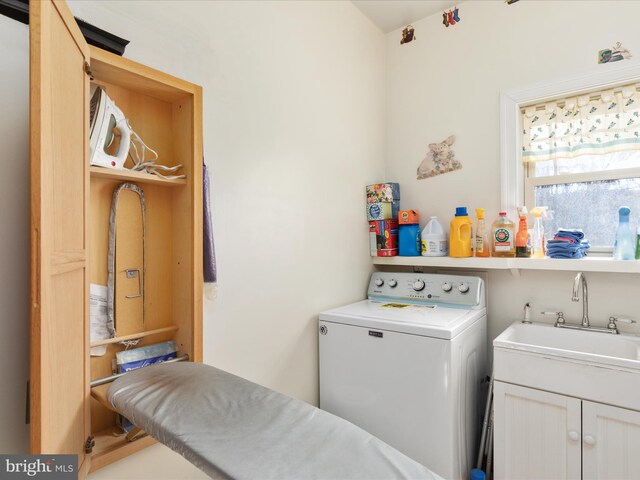 clothes washing area with cabinets, washer / dryer, and sink