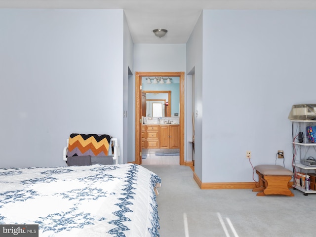 bedroom with ensuite bath and light carpet